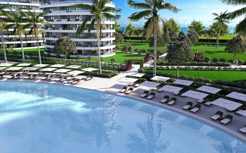 Ocean Life Residence — Geniş yüzme havuzu kenarında şezlong sıraları, arkada bloklar ve deniz (görselleştirme)
