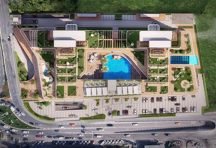 Kuşbakışı çekimde bloklar arasındaki peyzaj alanı havuzu çevreliyor. Yürüyüş yolları ve otopark site genelinde uzanıyor.